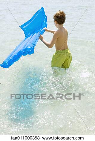 Boy carrying air mattress in sea View Large Photo Image Stock Photo - Boy carrying air mattress in sea. Fotosearch