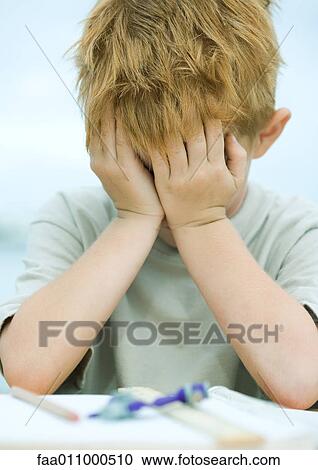 Boy covering face, homework on table in front of him View Large Photo Image Stock Image - Boy covering face, homework on table in front of him. Fotosearch