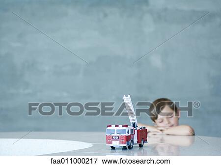 Boy dreaming behind toy firetruck View Large Photo Image Stock Photo - Boy dreaming behind toy firetruck. Fotosearch