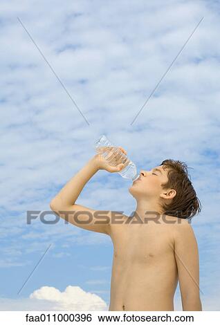 Stock Photograph - Boy drinking water from bottle, low angle view. Fotosearch