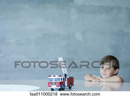 Boy looking at toy firetruck View Large Photo Image Stock Photo - Boy looking at toy firetruck. Fotosearch