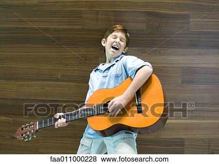 Boy playing guitar and singing View Large Photo Image Stock Photo - Boy playing guitar and singing. Fotosearch