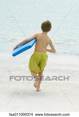 Boy running toward sea carrying body board View Large Photo Image Picture - Boy running toward sea carrying body board. Fotosearch
