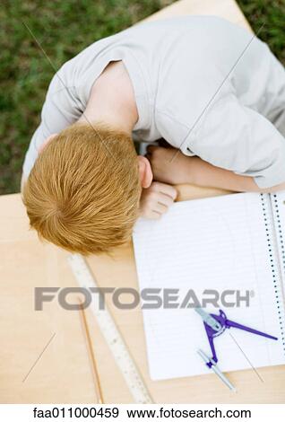Boy with head on table next to open notebook View Large Photo Image Stock Photo - Boy with head on table next to open notebook. Fotosearch