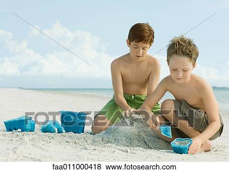 Boys building sand castle on beach View Large Photo Image Stock Photo - Boys building sand castle on beach. Fotosearch