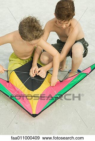 Stock Photo - Boys preparing kite on beach. Fotosearch