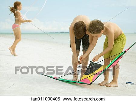 Stock Photography - Boys preparing kite on beach. Fotosearch