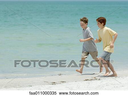 Boys running next to surf on beach View Large Photo Image Stock Photography - Boys running next to surf on beach. Fotosearch