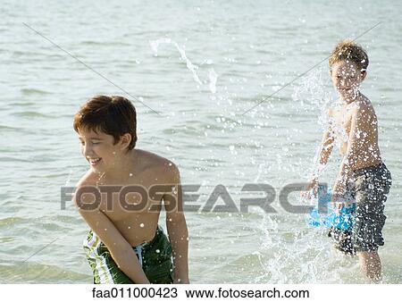 Boys splashing in ocean with buckets View Large Photo Image Stock Image - Boys splashing in ocean with buckets. Fotosearch