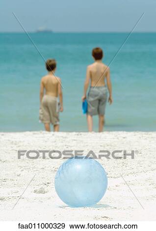 Boys standing near surf, ball in foreground View Large Photo Image Stock Photo - Boys standing near surf, ball in foreground. Fotosearch