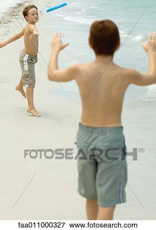 Stock Photo - Boys throwing frisbee on beach. Fotosearch