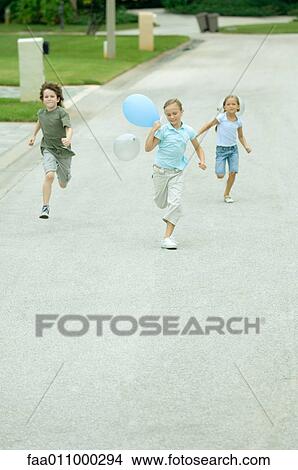 Picture - Children with balloons running through residential street. Fotosearch
