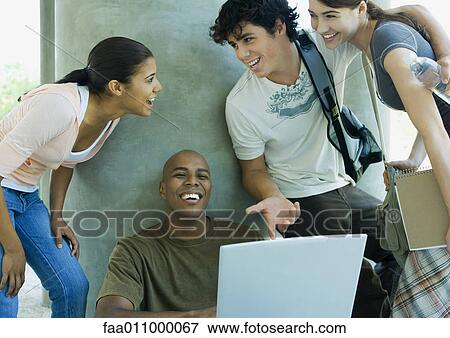 Stock Photo - College students looking at laptop and laughing. Fotosearch