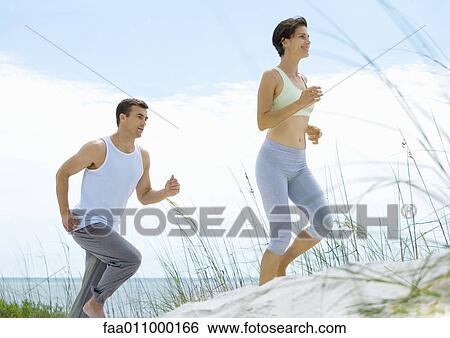 Stock Photograph - Couple jogging in dunes. Fotosearch