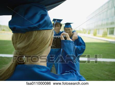 Stock Photograph - Female graduate taking photo of friends. Fotosearch