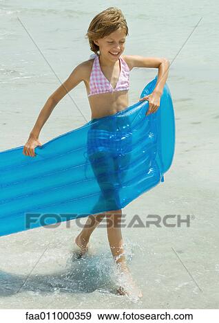 Girl carrying air mattress in surf View Large Photo Image Stock Photo - Girl carrying air mattress in surf. Fotosearch