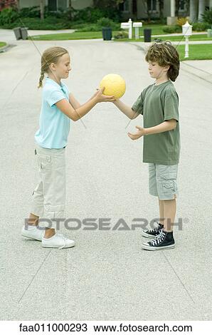 Girl handing boy ball in residential street View Large Photo Image Stock Image - Girl handing boy ball in residential street. Fotosearch