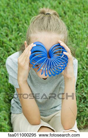 Stock Photography - Girl holding coiled spring in front of eyes. Fotosearch