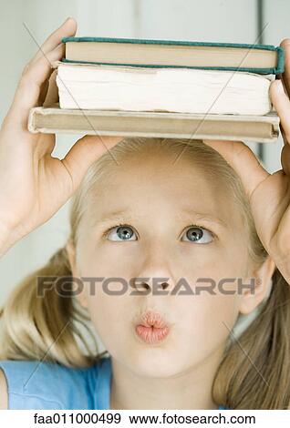 Girl holding stack of books on head, crossing eyes View Large Photo Image Stock Photo - Girl holding stack of books on head, crossing eyes. Fotosearch