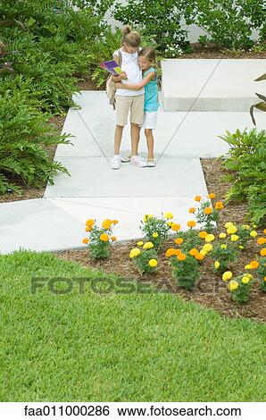 Girl hugging sister on walkway View Large Photo Image Stock Photograph - Girl hugging sister on walkway. Fotosearch