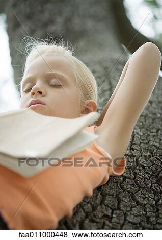 Girl in tree sleeping with book on chest View Large Photo Image Stock Photo - Girl in tree sleeping with book on chest. Fotosearch