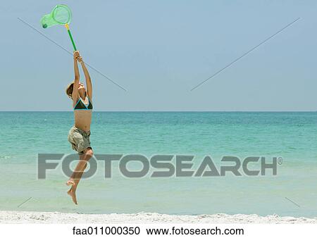 Girl jumping with fishing net on beach View Large Photo Image Stock Image - Girl jumping with fishing net on beach. Fotosearch
