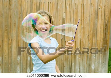 Girl making bubble with bubble wand View Large Photo Image Stock Photograph - Girl making bubble with bubble wand. Fotosearch