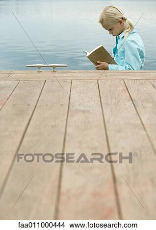 Girl reading book by water View Large Photo Image Picture - Girl reading book by water. Fotosearch