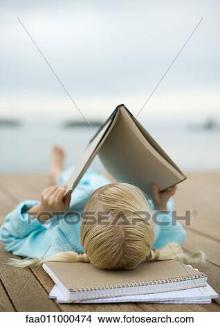 Picture - Girl reading book on dock. Fotosearch