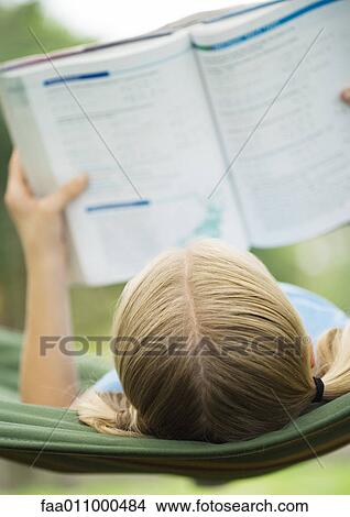 Picture - Girl reading school book on hammock. Fotosearch