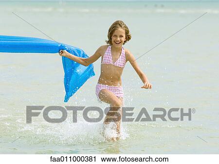 Girl running in surf with air mattress View Large Photo Image Stock Image - Girl running in surf with air mattress. Fotosearch