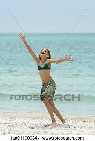 Stock Photo - Girl running with arms up on beach. Fotosearch