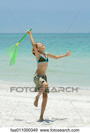 Girl standing with fishing net on beach View Large Photo Image Stock Photo - Girl standing with fishing net on beach. Fotosearch