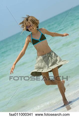 Stock Image - Girl stepping out of surf. Fotosearch