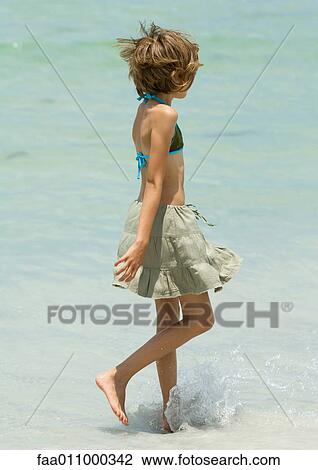 Stock Image - Girl walking in surf. Fotosearch