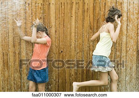 Stock Photo - Girls getting wet in sprinkler. Fotosearch
