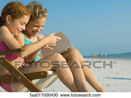 Girls reading book together on beach View Large Photo Image Stock Image - Girls reading book together on beach. Fotosearch