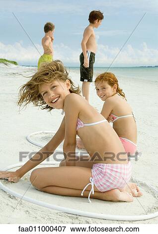 Girls sitting in rings, playing in sand on beach View Large Photo Image Stock Photo - Girls sitting in rings, playing in sand on beach. Fotosearch