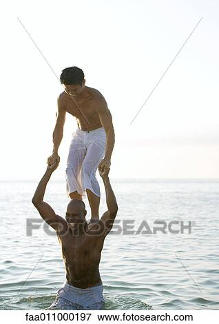 In sea, man standing on second man's shoulders View Large Photo Image Stock Photo - In sea, man standing on second man's shoulders. Fotosearch