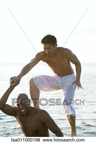 In sea, man stepping onto second man's shoulders View Large Photo Image Stock Photo - In sea, man stepping onto second man's shoulders. Fotosearch