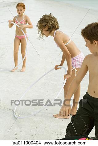 Picture - Kids playing with hoola hoops on beach. Fotosearch