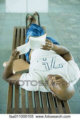 Male student lying on bench, reading View Large Photo Image Stock Image - Male student lying on bench, reading. Fotosearch