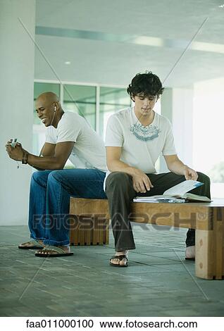 Male students sitting on bench on campus View Large Photo Image Stock Image - Male students sitting on bench on campus. Fotosearch