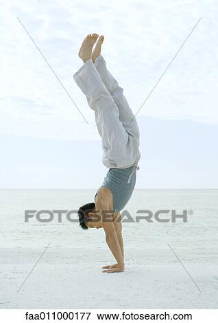 Stock Photo - Man doing handstand on beach. Fotosearch
