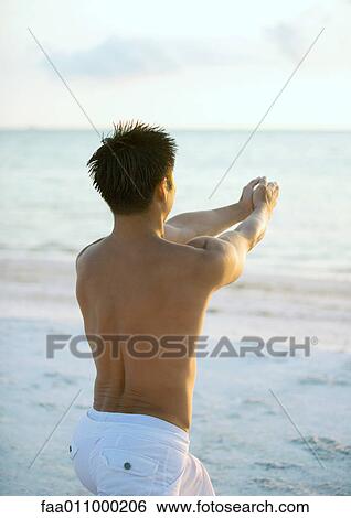 Stock Photograph - Man doing relaxation exercise on beach. Fotosearch