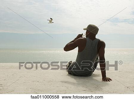 Man drinking water on beach View Large Photo Image Stock Photo - Man drinking water on beach. Fotosearch
