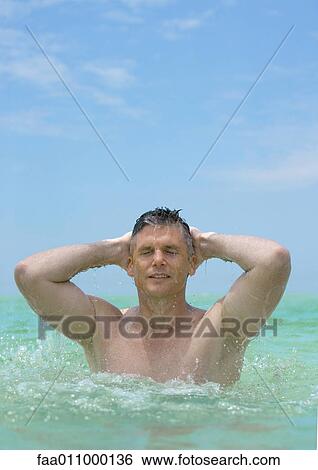 Man emerging from water, hands behind head View Large Photo Image Stock Photograph - Man emerging from water, hands behind head. Fotosearch