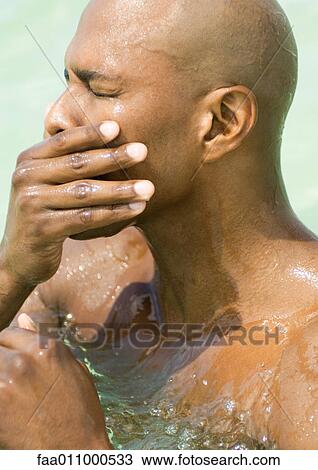 Man in water, wiping face with eyes closed, close-up View Large Photo Image Stock Image - Man in water, wiping face with eyes closed, close-up. Fotosearch