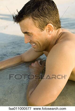 Stock Photo - Man lying in shallow water. Fotosearch