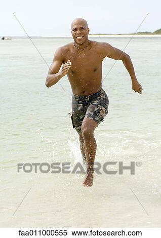 Stock Photography - Man running through surf. Fotosearch
